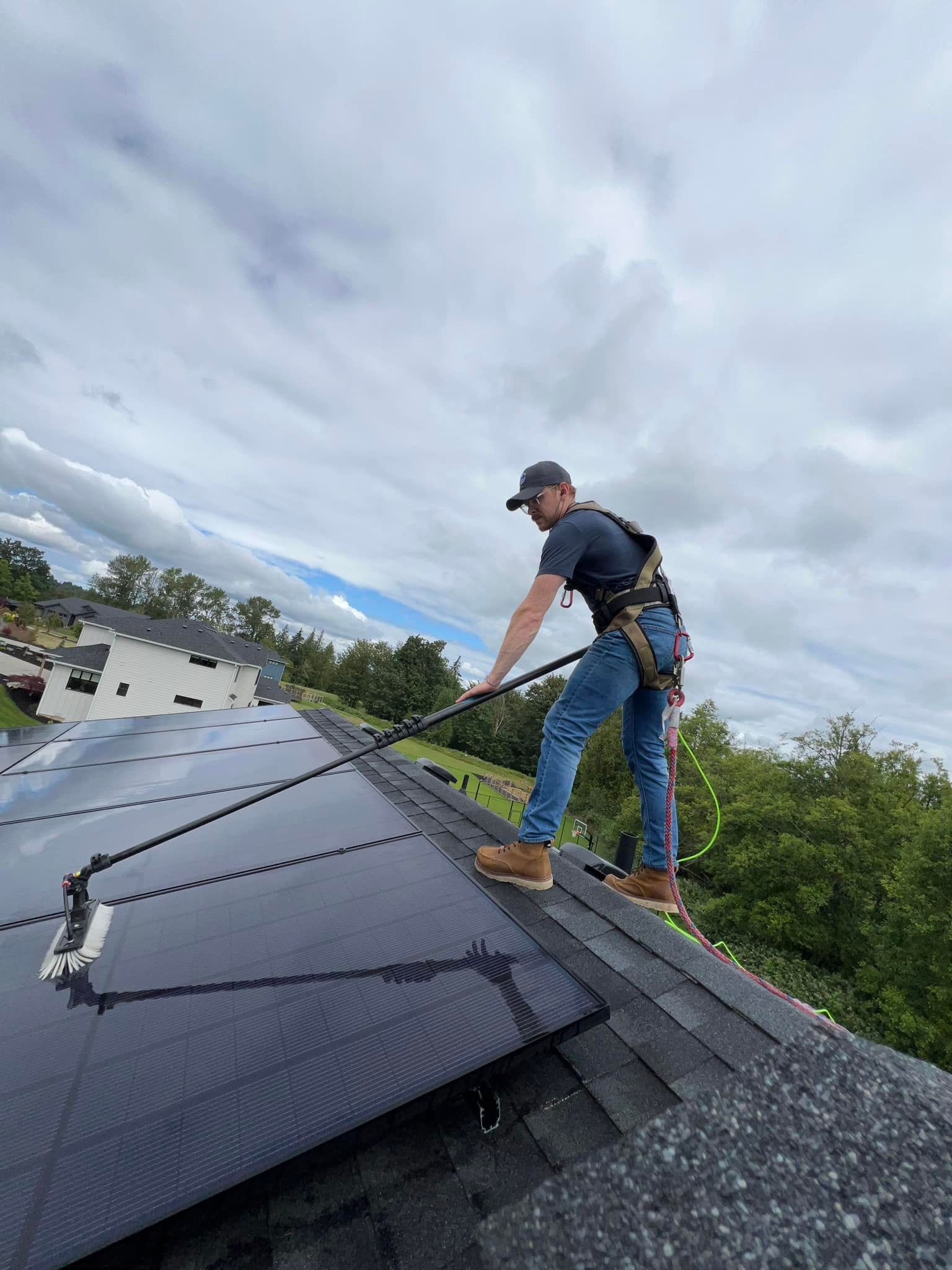 Diamond PT technician safely cleaning solar panels on a roof