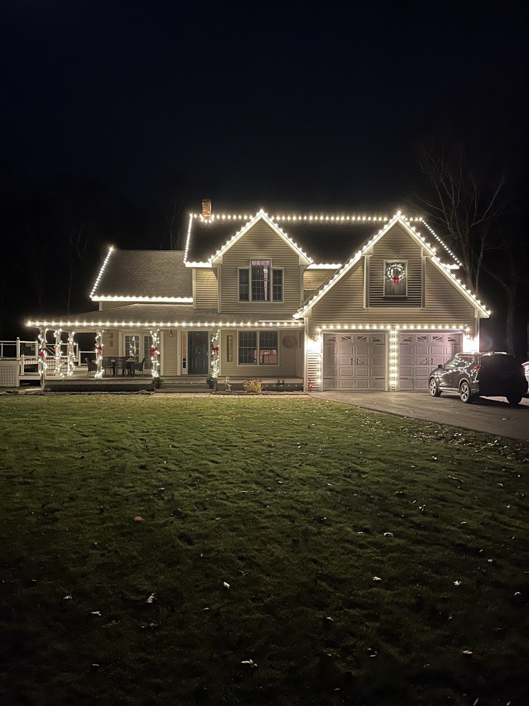 Clean white roofline and porch lighting installed on a two-story home at night by Diamond PT